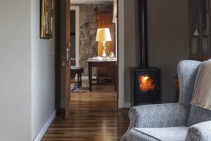 Gran parte de la casa tiene piso de madera y salamandras que, además de calefaccionar, duplican la capacidad del termotanque. Desde este cálido rincón, vista al escritorio de Patricio.