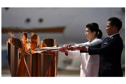 Los antiguos campeones olímpicos Saori Yoshida y Tadahiro Nomura encienden el pebetero de los Juegos de Tokio con la llama olímpica tras bajar del avión en que la trajeron de Grecia, el 20 de marzo de 2020 en la base áerea de Higashimatsushima (Japón)