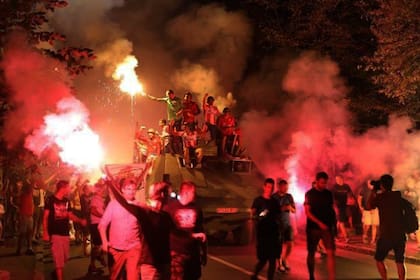 Los apasionados hinchas de Estrella Roja portan bengalas mientras siguen al tanque con los jugadores