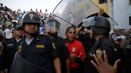 Los árbitros reciben protección especial en este evento porque la mitad de los espectadores no están de acuerdo con sus acciones, repudian tirándoles botellas y huesos de pollo, durante el campeonato de fútbol callejero Mundialito de El Porvenir en Lima, Perú.