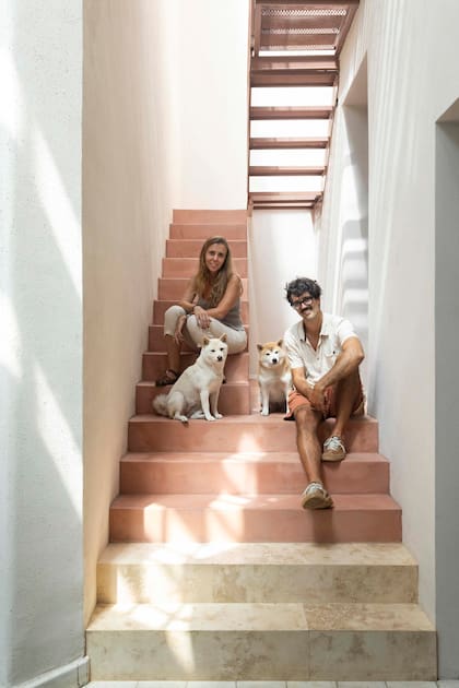 Los arquitectos Laia Rodríguez Tosti y Pablo Quintana posan en la escalera que lleva al nivel de los cuartos y la terraza. Para los peldaños más bajos se eligieron placas de Travertino (Oscar Revestimientos), el resto del primer tramo se completó con un acabado cementicio.