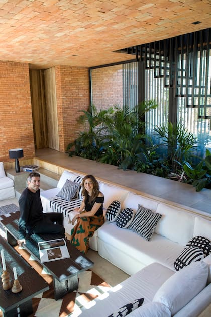 Los arquitectos Matías Mosquera y Camila Gianicolo, de Atelier M, sentados en sillones con manta ‘Bambú’ y almohadones con estampados geométricos en blanco y negro (Mercedes Segura Deco).