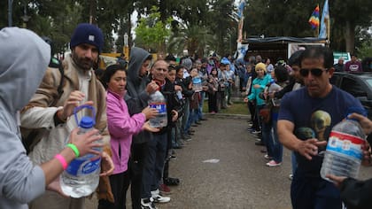Los asambleístas descargan los 2000 litros de agua mineral que recibieron como donación