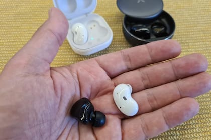 Los auriculares de Nobles (negros) junto a los Galaxy Buds Live de Samsung (blancos) a modo de comparación de tamaño; los de Noblex son muy compactos y apenas sobresalen de la oreja