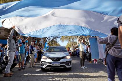 Los autos pasan por un túnel hecho con una bandera, en Mendoza