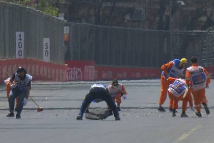 Los auxiliares del circuito de Bakú colocan la alcantarilla que provocó el accidente y limpian el circuito.