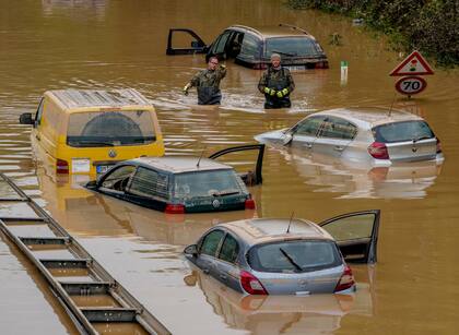 Los ayudantes buscan víctimas en automóviles inundados en una carretera en Erftstadt, Alemania.
