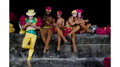 Los bailarines utilizan un punto de acceso a Internet antes de actuar en el Carnaval de La Habana