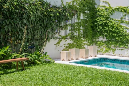 Los bancos cúbicos de madera macizas escoltan la pileta y sirven como trampolín. En la pared hay una estructura modular de hierro negro.