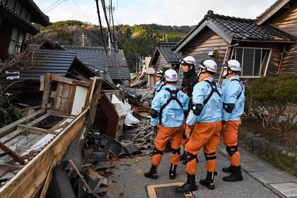 Los bomberos inspeccionan casas de madera colapsadas en Wajima, prefectura de Ishikawa, el 2 de enero de 2024, un día después de que un importante terremoto de magnitud 7.5 sacudiera la región de Noto.