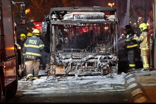 Los bomberos israelíes revisan un autobús quemado en la ciudad israelí de Holon, cerca de Tel Aviv
