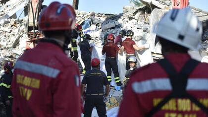Los bomberos recuperan el cuerpo sin vida de una víctima entre los escombros de un edificio derruido en Amatrice
