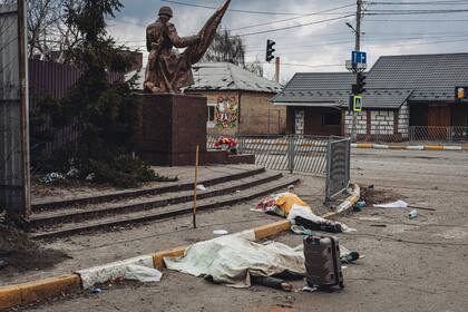 Los cadáveres de las personas muertas por los bombardeos rusos yacen cubiertos en la calle en la ciudad de Irpin, Ucrania, el domingo 6 de marzo de 2022. 