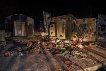 Los cadáveres de soldados del ejército sirio y combatientes aliados yacen al lado de un vehículo militar sirio tras ser presuntamente abatidos en combate por elementos de la oposición en Alepo, Siria, la madrugada del sábado 30 de noviembre de 2024. (AP Foto/Omar Albam)