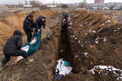 Los cadáveres son colocados en una fosa común en las afueras de Mariupol, Ucrania, el miércoles 9 de marzo de 2022, ya que la gente no puede enterrar a sus muertos debido a los fuertes bombardeos de las fuerzas rusas.