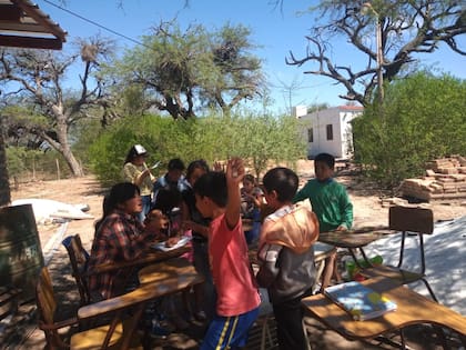 Los chicos se sientan a hacer la tarea bajo los árboles