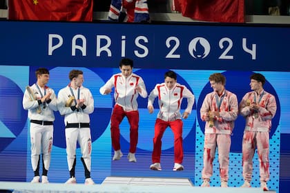Los chinos Lian Junjie y Yang Hao, centro, festejan su medalla de oro flanqueados por los medallistas de plata, los británicos Thomas Daley y Noah Williams, izquierda, y los de bronce, Rylan Wiens y Nathan Zsombor-Murray, de Canadá, en el podio de plataforma sincronizada para hombres de los Juegos Olímpicos de París 2024 el lunes 29 de julio de 2024, en Saint-Denis, Francia. (AP Foto/Lee Jin-man)