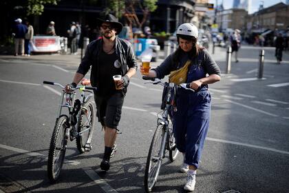 Los clientes en bicicleta retiran su cerveza desde un pub en Broadway Market, Londres, el 5 de junio de 2020, a medida que se alivia el bloqueo por la pandemia de coronavirus