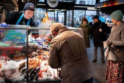 Los clientes se muestran en el mercado de pescado en Torvehallerne en Copenhague el 1 de febrero de 2022, cuando Dinamarca se convierte en el primer país de la UE en levantar las restricciones 