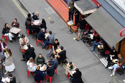 Los clientes se sientan en las mesas al aire libre de los bares reabiertos en Soho en Londres el 4 de julio de 2020