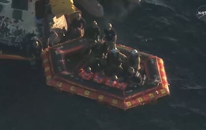 Los cuatro astronautas, vestidos de naranja, en el bote de rescate de la Marina de EE.UU.