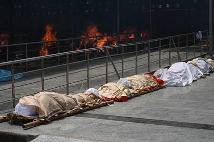 Los cuerpos de las víctimas del coronavirus se alinearon antes de la cremación en un campo de cremación en Nueva Delhi el 28 de abril de 2021