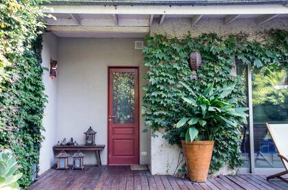 Los detalles, como una puerta pintada de rojo o los porta velas de estética asiática, le aportan singularidad al jardín.