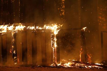 Una cerca de madera es consumida por las llamas en Santa Cruz, California