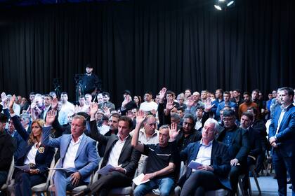 Los dirigentes en la Asamblea General Ordinaria 2024 de la Asociación del Fútbol Argentino en el predio de Ezeiza, y un voto a mano alzada