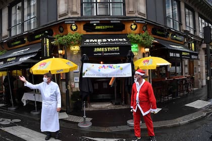 Los dueños de restaurantes se paran junto a una pancarta que dice "Morir, sí, ¡pero con estilo!" frente al restaurante "Le Mesturet" en París el 2 de octubre de 2020, tras las nuevas restricciones