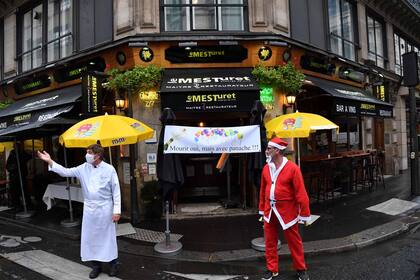 Los dueños de restaurantes se paran junto a una pancarta que dice "Morir, sí, ¡pero con estilo!" frente al restaurante "Le Mesturet" en París el 2 de octubre de 2020, tras las nuevas restricciones