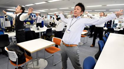 Los empleados de una empresa de tecnología mientras hacen ejercicios en sus oficina, después de la hora del almuerzo en Tokio.
