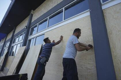 Los empleados de una tienda de muebles colocan tablas en las ventanas para protegerlas antes de la llegada prevista del huracán Beryl, en Playa del Carmen, el miércoles 3 de julio de 2024
