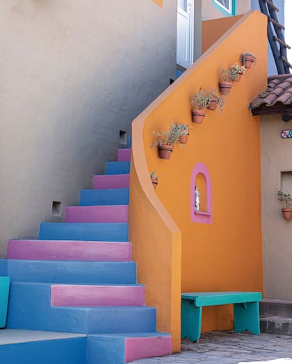 Los escalones de colores y las pequeñas macetas terracota contra el fondo naranja marcan el ritmo (y suman alegría!) en esta escalera