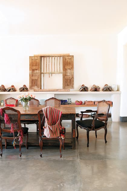 Los estantes hechos con gruesos tablones de madera y el cemento alisado del piso descontacturan y hacen funcionar las sillas Luis XV de una manera canchera