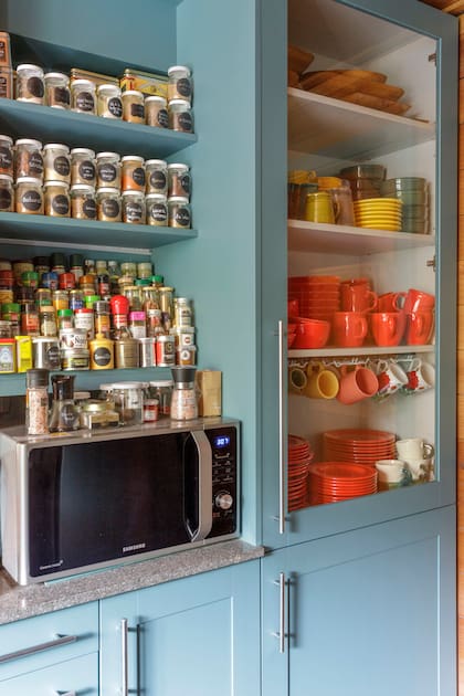 Los estantes, repletos de vajilla colorida, utensilios y condimentos, son reflejo de la pasión por la cocina de la dueña de casa.