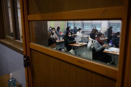 Los estudiantes esperan el inicio de un examen de ingreso a la universidad en medio de la pandemia del coronavirus en una sala de exámenes en Seúl el 3 de diciembre de 2020.