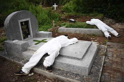 Los excavadores de tumbas exhaustos descansan entre los funerales en un cementerio designado para las víctimas de Covid-19 en Bandung, Java Occidental, Indonesia