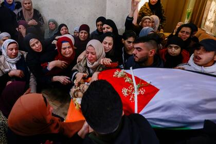 Los familiares de Yassin al-Asmar, fallecido en enfrentamientos nocturnos con las fuerzas de seguridad israelíes, lloran su cuerpo en Beitunia, cerca de la ciudad de Ramallah en la ocupada Cisjordania, durante su funeral el 28 de noviembre de 2023. 