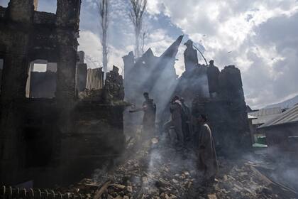 Hombres de Cachemira desmantelan una parte de una casa destruida en un tiroteo en la aldea de Tral, al sur de Srinagar, Cachemira