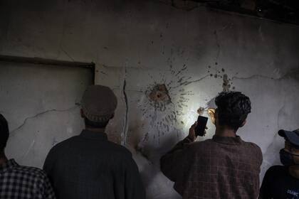 Un niño de Cachemira intenta sacar una bala de la pared de una casa dañada después de un tiroteo en Tral, al sur de Srinagar