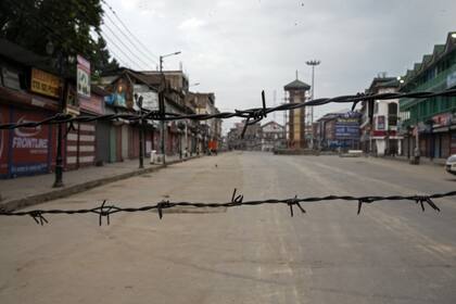 Vista de una calle desierta a través del alambre de púas establecido como bloqueo durante el toque de queda en Srinagar