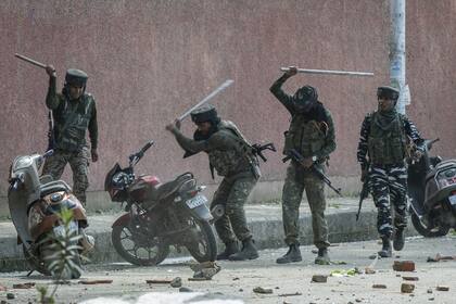 Soldados paramilitares indios rompen motocicletas estacionadas afuera de una universidad mientras se enfrentan con estudiantes que protestaban por la presunta violación de una niña de 3 años en Srinagar