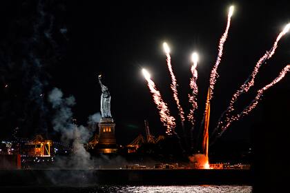 Los fuegos artificiales lanzados desde una barcaza iluminan el puerto de Nueva York y la Estatua de la Libertad