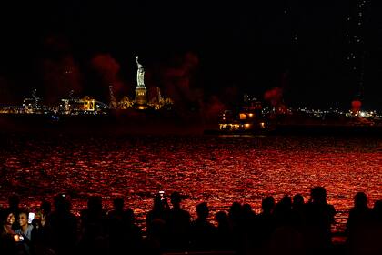 Los fuegos artificiales se reflejan en el agua, con la Estatua de la Libertad al fondo