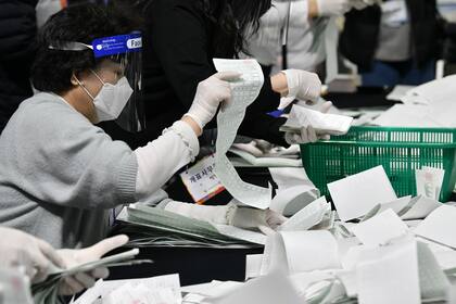 Los funcionarios electorales de Corea del Sur clasifican los documentos de votación para el conteo de votos en las elecciones parlamentarias en un gimnasio en Seúl el 15 de abril de 2020