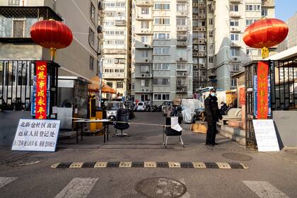 Los guardias en un complejo de apartamentos en el vecindario de Dongzhimen en Pekín controlan la temperatura de las personas antes de ingresar el 3 de febrero de 2020