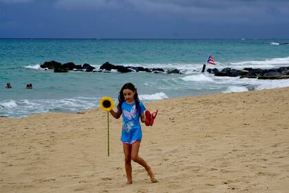 Una niña camina por la playa bajo un cielo que ya muestra señales de tormenta