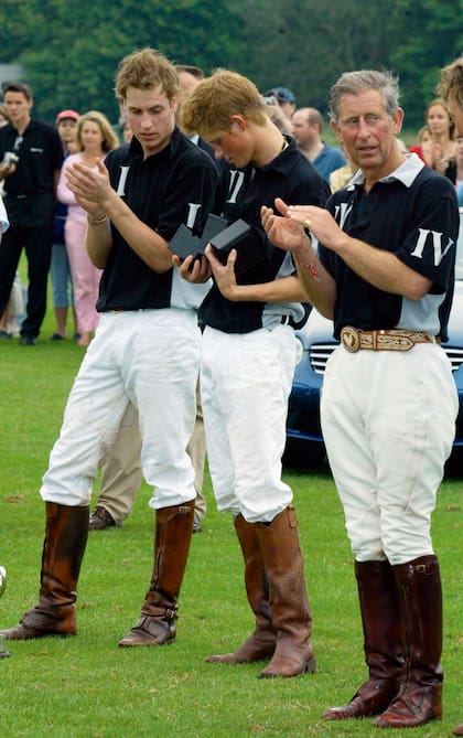 Los hermanos heredaron de su padre, el Rey, la pasión por el polo. En la foto, William y Carlos aplauden a Harry en una ceremonia de premiación tras una día de competencia en Gloucestershire, a donde Su Majestad tiene Highgrove House, su residencia preferida, desde 1980.