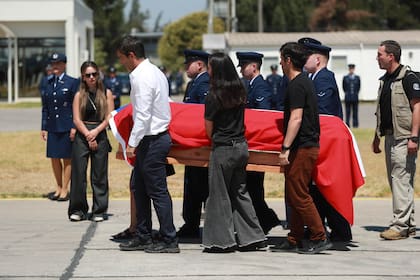 Los hijos de Sebastián Piñera trasladan los restos del expresidente en el aeropuerto de Santiago (Photo by RAUL BRAVO / AFP)